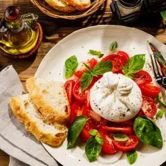 Pyszna burrata, czyli straciatella ser, z pomidorami i bazylią, podana z chrupiącym pieczywem i oliwą.