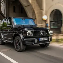 Czarny Mercedes G63 z okrągłymi światłami LED pędzi pod wiaduktem.