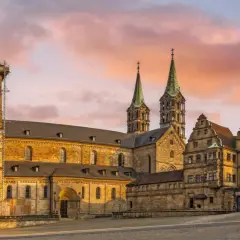 Bamberg Altstadt: Majestätischer Kaiserdom mit Türmen im Abendlicht, umgeben von historischen Gebäuden.