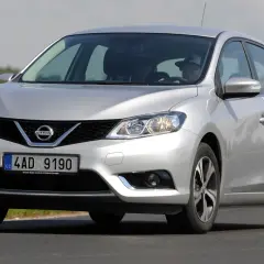 Srebrny Nissan Pulsar w ruchu drogowym. Zbliżenie na przód auta, widoczne reflektory, grill z logo Nissan i tablica rejestracyjna. Poznaj nissan pulsar wymiary.