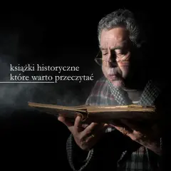 Starszy mężczyzna w okularach pochyla się nad starą księgą, szukając najlepszych książek historycznych.