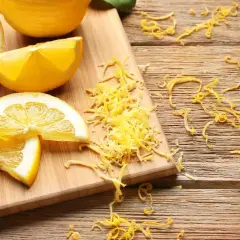 Świeże cytryny pokrojone w ćwiartki i plasterki, obok garść startej skórki. Czy można jeść skórkę z cytryny? Tak, jest aromatyczna!