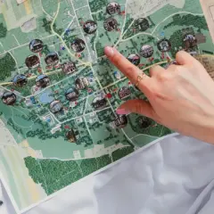 Ręka wskazuje na mapę Nałęczowa, pokazującą zabytki i atrakcje. Mapa przypomina o historii wszystkich województw w Polsce.