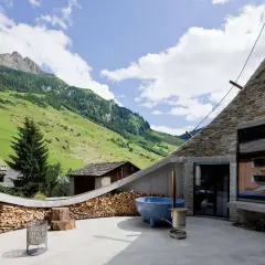 Dekorativ gestapeltes Brennholz umrahmt den Grill und die Terrasse mit Bergblick. Ein blaues Becken und ein Feuerkorb laden zum Entspannen ein.
