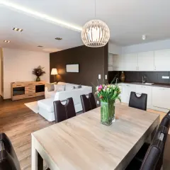 Salon moderne avec cuisine ouverte, table en bois et tulipes. Idéal pour un primo accédant cherchant un espace de vie lumineux et fonctionnel.