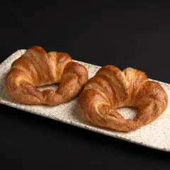 Dos croissants dorados, listos para disfrutar. El hojaldre crujiente invita a hacer croissant con hojaldre casero.