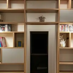 Parete in legno fai da te con libri, DVD e decorazioni. Illuminazione discreta valorizza gli oggetti.