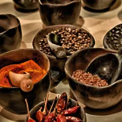 Miseczki z przyprawami: kurkumą, ziarnami pieprzu, ziarnami zbóż i suszonymi papryczkami chili.