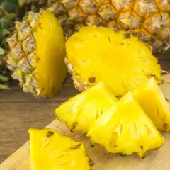 Soczyste kawałki ananasa na desce, obok całego owocu. Czy ananas jest zdrowy? Tak, to bomba witaminowa!
