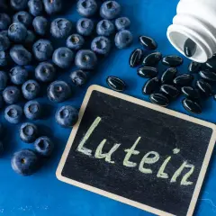 Jagody i kapsułki suplementu diety z napisem "Luteina" na tabliczce. Luteina na oczy wspiera zdrowie wzroku.