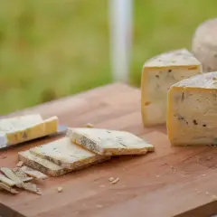 Formaggio stagionato con venature di muffa blu e verde su un tagliere di legno. Alcune fette sono già state tagliate.