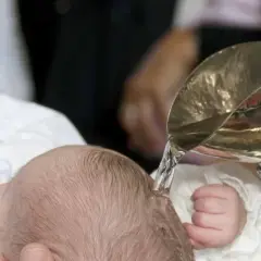 Taufe eines Babys mit Wasser aus einem silbernen Gefäß.