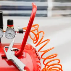 Detalles de un compresor de aire rojo con manómetros y pistola. Aprende como limpiar un compresor de aire para un óptimo funcionamiento.