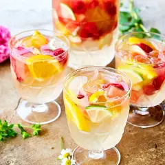 Tre glas med uppfriskande sangria vit fyllda med frukt och is. En perfekt sommardrink!