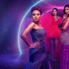 Fyra kvinnor i glittrande klänningar poserar framför en neonljusring. En scen som hämtad ur de mest glamorösa fashion movies.