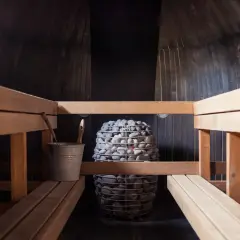 Drewniana sauna z kamiennym piecem. Czy sauna po treningu jest zdrowa? Odpoczynek i regeneracja po wysiłku.