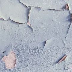 Texture d'une peinture qui s'écaille, révélant la texture rugueuse du mur sous-jacent, témoignant de l'humidité.