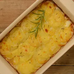 En gyllene pommes anna i en ugnsform, toppad med en rosmarinkvist. Perfekt till helgmiddagen.
