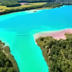 Turkusowe jezioro otoczone zielenią, przypominające polskie Malediwy. Piaskowe plaże i bujna roślinność tworzą malowniczy krajobraz.