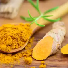 Kurkuma-Pulver auf einem Holzlöffel und frische Wurzeln. Kurkuma kann bei Durchfall helfen.