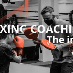 A coach demonstrates boxing techniques to a young boxer, highlighting the ins and outs of coaching boxing.