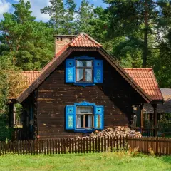 Drewniany domek z niebieskimi okiennicami, idealny na wypoczynek. Sprawdź, gdzie można wykorzystać bon turystyczny bez noclegu!