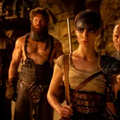 Furiosa z "Sagi Mad Max" w otoczeniu groźnych towarzyszy, gotowa do walki w postapokaliptycznym świecie.