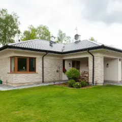 Uroczy, niewielki dom z kamienną elewacją i zadbanym ogrodem.