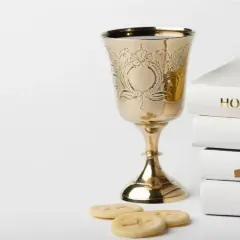 Złoty kielich, stos białych ksiąg z napisem "HOLY BIBLE", różaniec i opłatki. Symbolika sakramentu, który może być odnotowany w akcie chrztu.