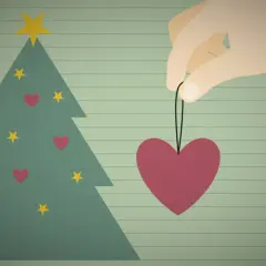 Ein Herz als Weihnachtsbaumschmuck, gehalten von einer Hand, symbolisiert eine besinnliche Weihnacht voller Liebe.