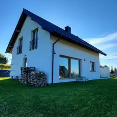 Biały dom pod klucz, gotowy do zamieszkania, na zielonej działce.