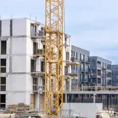 Budowa osiedla mieszkaniowego z żurawiem budowlanym i nowymi budynkami.