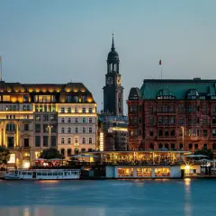Wieczorny widok na port w Hamburgu, gdzie tętni życie, a budynki oświetlone tworzą malowniczy krajobraz.