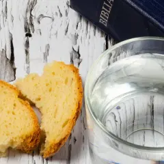 Chleb i woda na drewnianym stole, obok Biblii. Symbolika Wielkiego Piątku i postu.