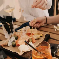 Leckereien auf einer Holzplatte, wie auf einer food pairing tabelle. Dazu Weißwein und ein Aperol Spritz.