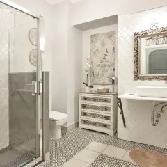 Elegancka łazienka w stylu klasycznym z prysznicem, toaletą, umywalką i ozdobną komodą.