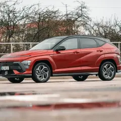 Czerwony Hyundai Kona Hybrid, idealny do miasta, z niskim spalaniem. Stylowy SUV na mokrej nawierzchni.
