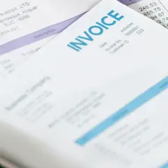 Stos dokumentów, w tym faktury i listy przewozowe, z widocznymi danymi firm i kwotami.