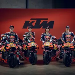 Pilotos de MotoGP KTM posan con sus motos de carreras naranjas y negras, listas para la competición.