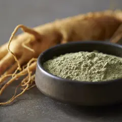 Radice di ginseng essiccata e polvere finissima in una ciotola, per capire ginseng come è fatto.