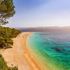 Traumhafter kroatischer Strand mit Pinienwald und türkisfarbenem Wasser. Menschen entspannen sich am Zlatni Rat Strand.