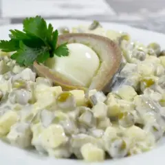 Sałatka z jajkiem, groszkiem i śledziem po japońsku, udekorowana natką pietruszki.