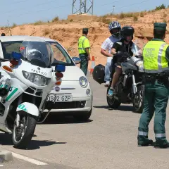Agente de tráfico detiene a motoristas. Posible multa por llevar pasamontañas.