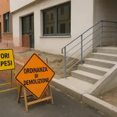 Segnali stradali indicano "Lavori sospesi" e "Ordinanza di demolizione" davanti a un cantiere. L'edilizia libera è ferma.