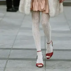 Jambes portant une chaussure ouverte avec collant blanc en dentelle, robe rose et manteau de fourrure.