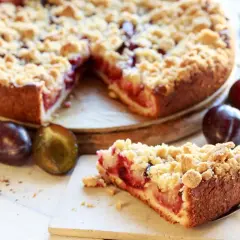 Saftiger Pflaumenkuchen mit Streuseln, perfekt für ein leckeres Pflaumenkuchen Rezept. Frische Pflaumen und Zimt daneben.
