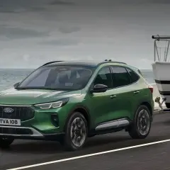 Zielony Ford Kuga z przyczepą i łodzią, idealny na wakacyjne wypady. Sprawdź ford kuga cena!