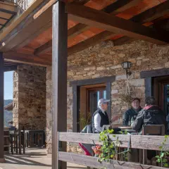 Gente disfrutando en la terraza de uno de los restaurantes de Horcajuelo de la Sierra, con vistas a la montaña.