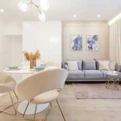 Nowoczesny salon z jadalnią, gdzie subtelne oświetlenie LED tworzy przytulną atmosferę. Jasne meble, pastelowa sofa i dekoracje tworzą spójną całość.