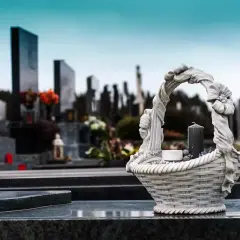 Kamienna ozdoba na nagrobku, symboliczny wiersz dla zmarłej mamy. W tle cmentarz, nagrobki i znicze.